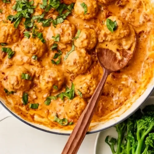 Marry Me Meatballs in a large cast iron skillet with creamy sun-dried tomato sauce, fresh basil garnish, and grated parmesan on top